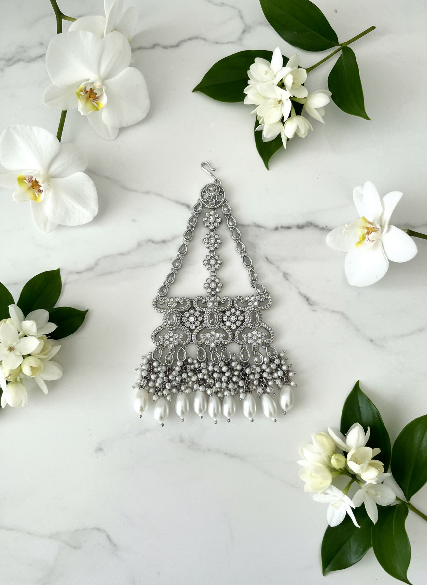 Silver maang tikka on marble with flowers