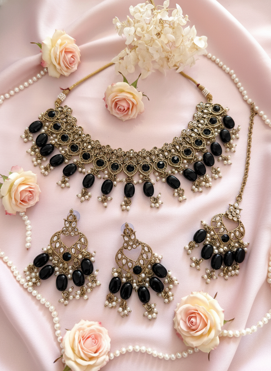 Black and gold jewellery set on pink background