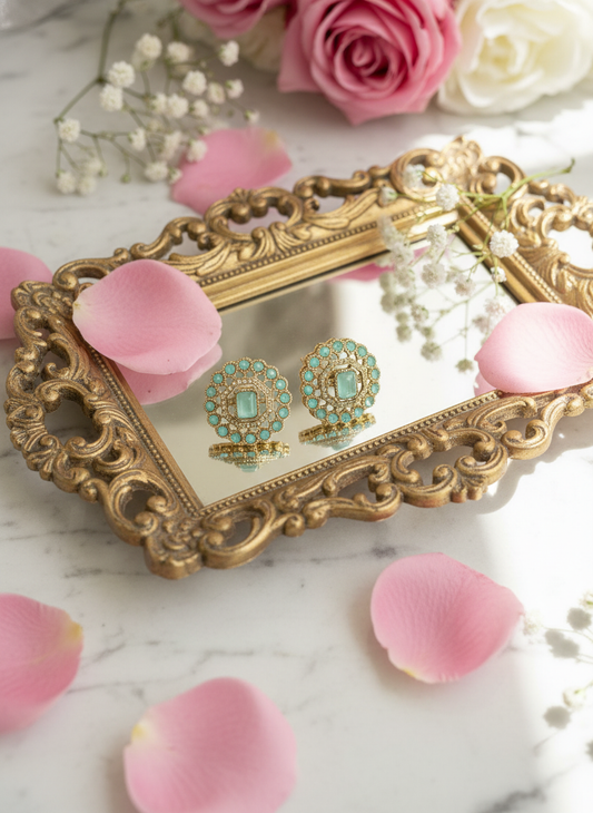 Turquoise earrings on gold tray with rose petals